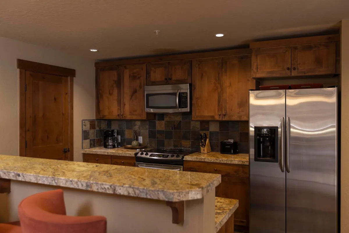 A cozy kitchen space with granite countertops, stainless steel appliances, wood cabinetry, and a colorful backsplash. The open concept design encourages lively gatherings and effortless meal preparation.